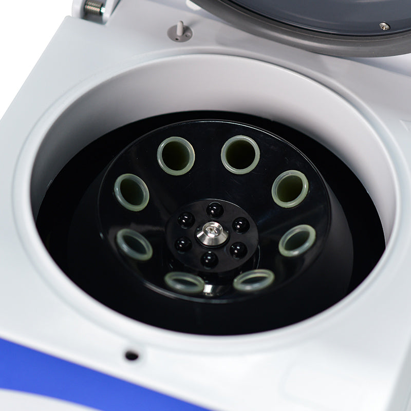 A top-down view of a centrifuge machine with a black centrifugal disc in the center surrounded by a white nutbolt. 
